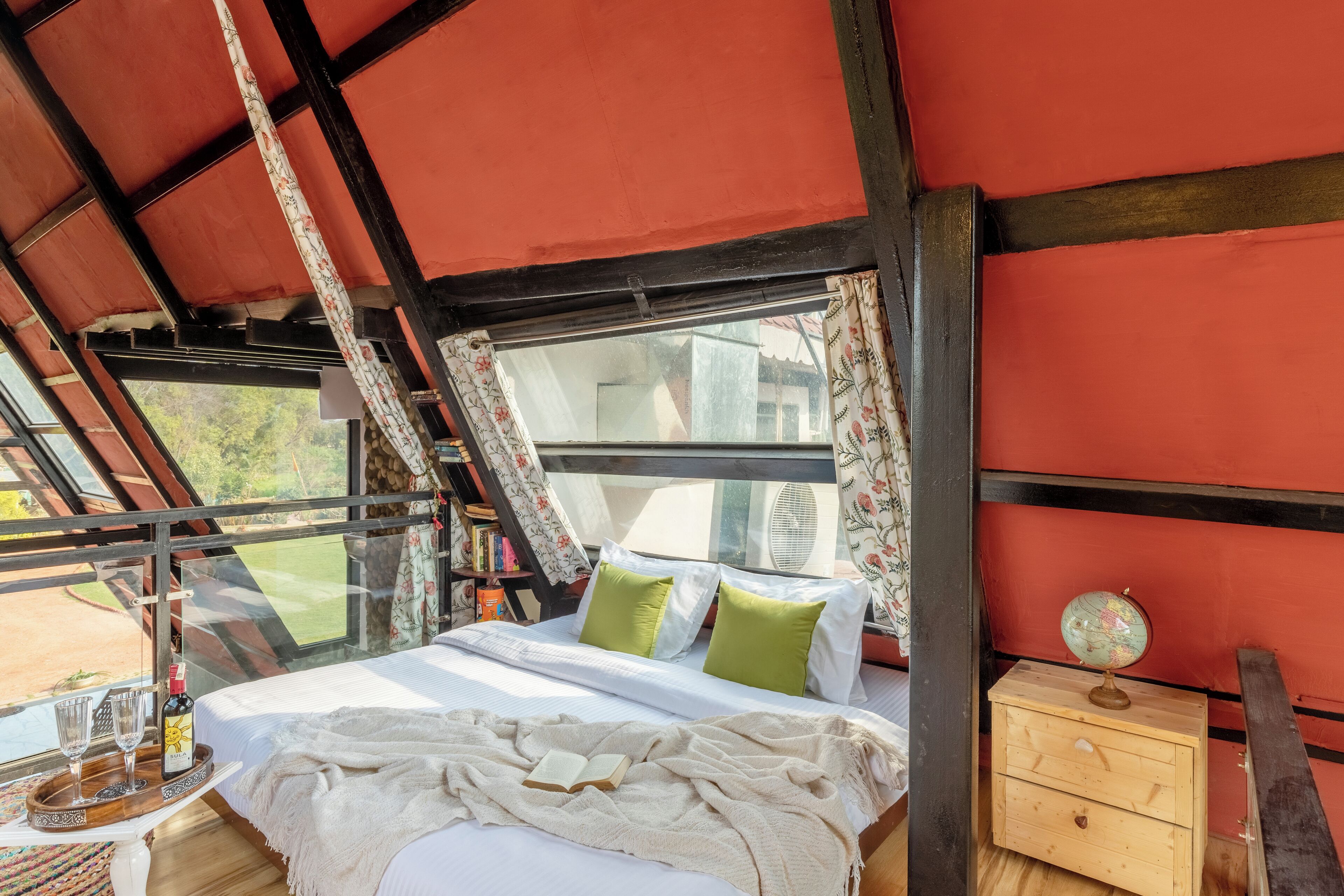 A bedroom with a bed, pillows, a bedside table with a globe, and a window with curtains.