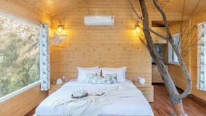 Quarto de cabana de madeira com cama, almofadas, mesa de cabeceira e janela.