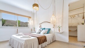 A bedroom with a bed, bedside table, hanging lights, and a view of the outdoors. - Holiday Home 'Casa Azul' with Sea View, Private Terrace & Wi-Fi (Las Palmas)