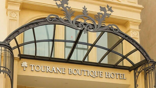 A building with a sign reading "TOURANE BOUTIQUE HOTEL" above a staircase leading to the entrance. - Tourane Boutique Hotel (Da Nang)
