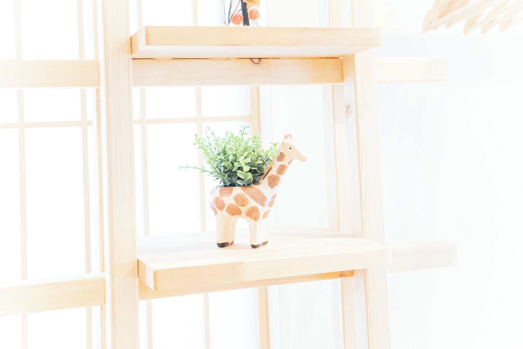 A wooden shelf with a giraffe-shaped planter holding green plants.