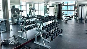 A gym with various exercise equipment, including dumbbells and weight machines. - FIRST CLASS | Studio | Cozy Chic Retreat (Marina)