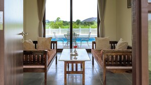 A room with a view of a pool and mountains. There is a table with chairs and two sofas. - Nature Jawai Retreat | Luxury Private Pool Villa Resort, Jawai (Bali)