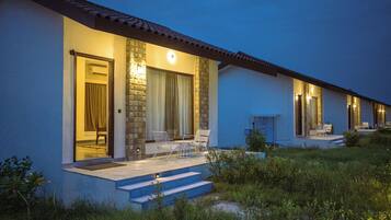 Un edificio moderno con facciata in pietra, un'area salotto esterna coperta con sedie e una scalinata che conduce all'ingresso.