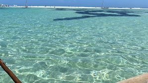 Vista despejada de una playa con aguas tranquilas y una costa lejana.