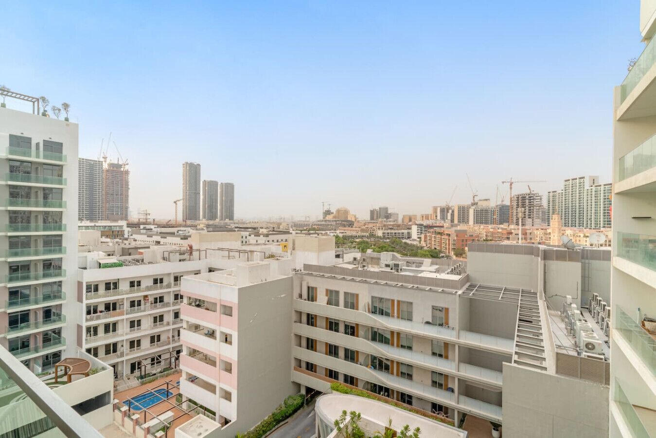 Un edifici residencial de grans alçades amb nombroses balcons, una piscina al terrat i vista a la ciutat.