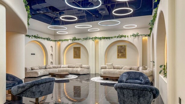 A modern spa with a central seating area, multiple sofas, and a reflective floor. - FIRST CLASS | Studio | Minimalist Chic Retreat (JVC)