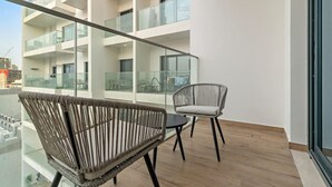 A modern apartment with a balcony, wicker chairs, and a glass railing. - FIRST CLASS | Studio | Minimalist Chic Retreat (JVC)