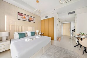 Una habitació d'hotel moderna amb un llit gran, taules de nit, un escriptori amb cadira i una zona de menjador.