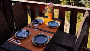 Een eethoek met een tafel voor vier personen, met uitzicht op een bergachtig landschap.
