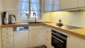 Une cuisine moderne avec des armoires blanches, une hotte de cuisinière en acier inoxydable et un lave-vaisselle intégré.