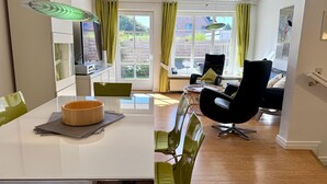 Une cuisine moderne avec un coin repas, comprenant une table blanche, des chaises vertes et une chaise noire.