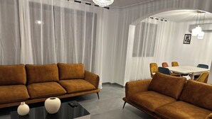 A modern living room with two brown sofas, a black coffee table, and a dining area with a white table and chairs. - Cosy and Comfortable House (Prades)