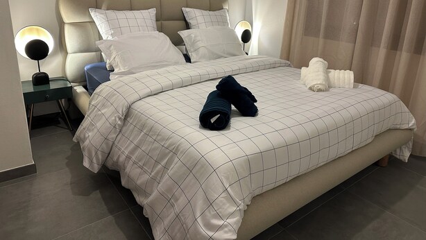 A neatly made bed with a checkered bedspread, two pillows, and a folded towel on the side. - Cosy and Comfortable House (Prades)