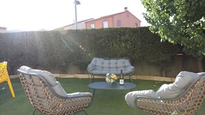 A patio with two wicker chairs and a table, surrounded by a hedge and a building in the background. - Cosy and Comfortable House (Prades)