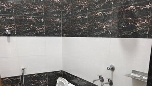 A bathroom with a toilet, bidet, and a bucket.