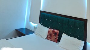 A modern bedroom with a bed, a ceiling fan, and blue ambient lighting.