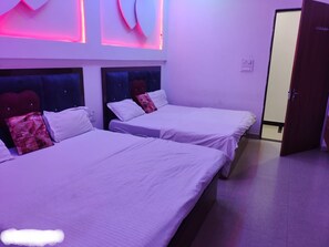 A room with two beds, each with a headboard, white bedding, and a single decorative pillow. - Shyam Krapa Hotel (Shri Madhopur)