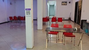A spacious indoor area with a reception desk, red chairs, and a long table.