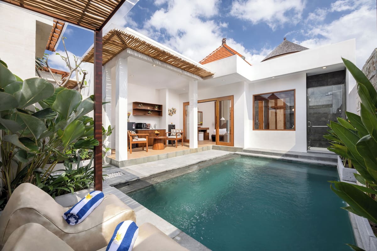 Une maison moderne dotée d’une piscine, d’un coin repas et d’une grande porte-fenêtre coulissante.