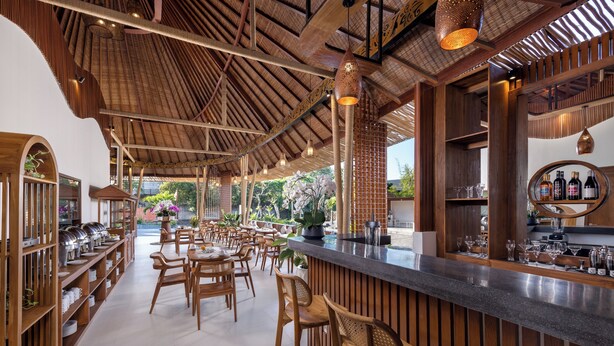 A restaurant with a wooden interior, a bar area, and a view of the outdoors. - La Tropica Canggu Bali (Buduk)
