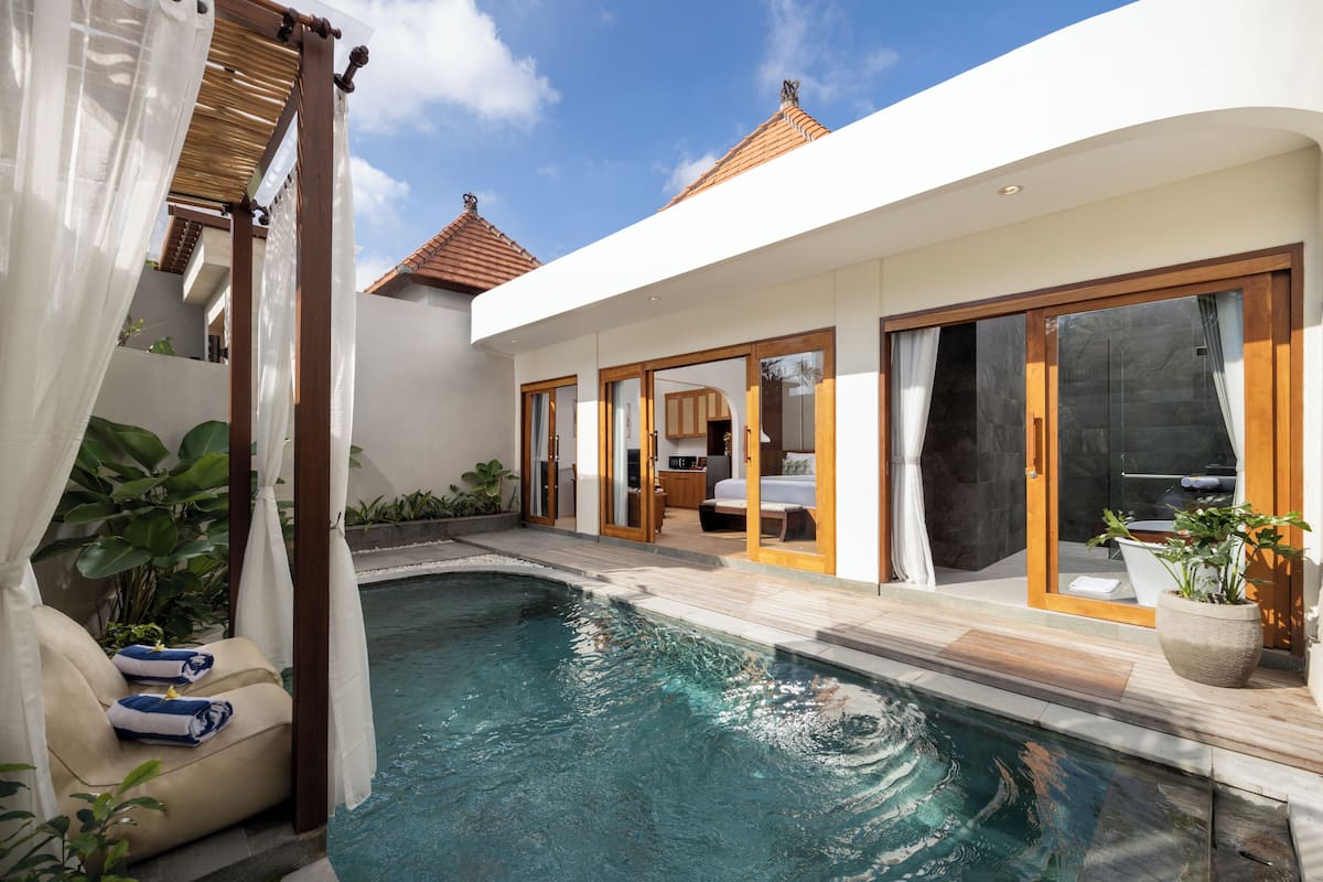 Un espace piscine extérieur moderne, doté d’une terrasse en bois, d’une chaise longue et d’une plante en pot.