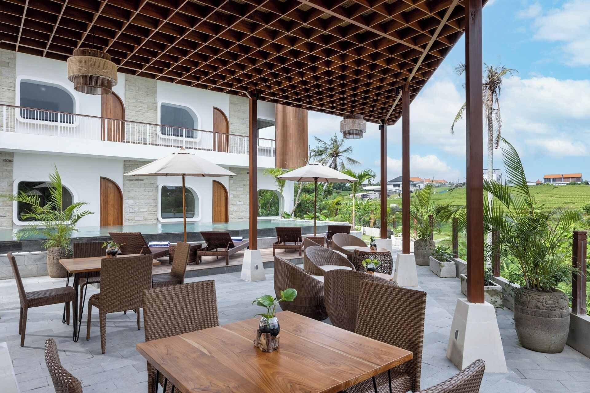 Un patio al aire libre con mobiliario de mimbre, una piscina y vistas a un paisaje exuberante.