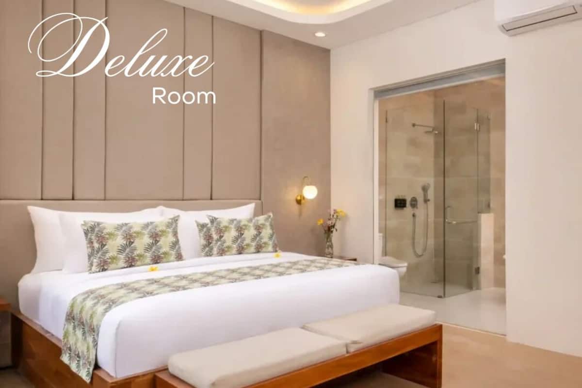 Une chambre à coucher moderne avec un grand lit, un banc, une douche en verre et un luminaire fixé au mur.