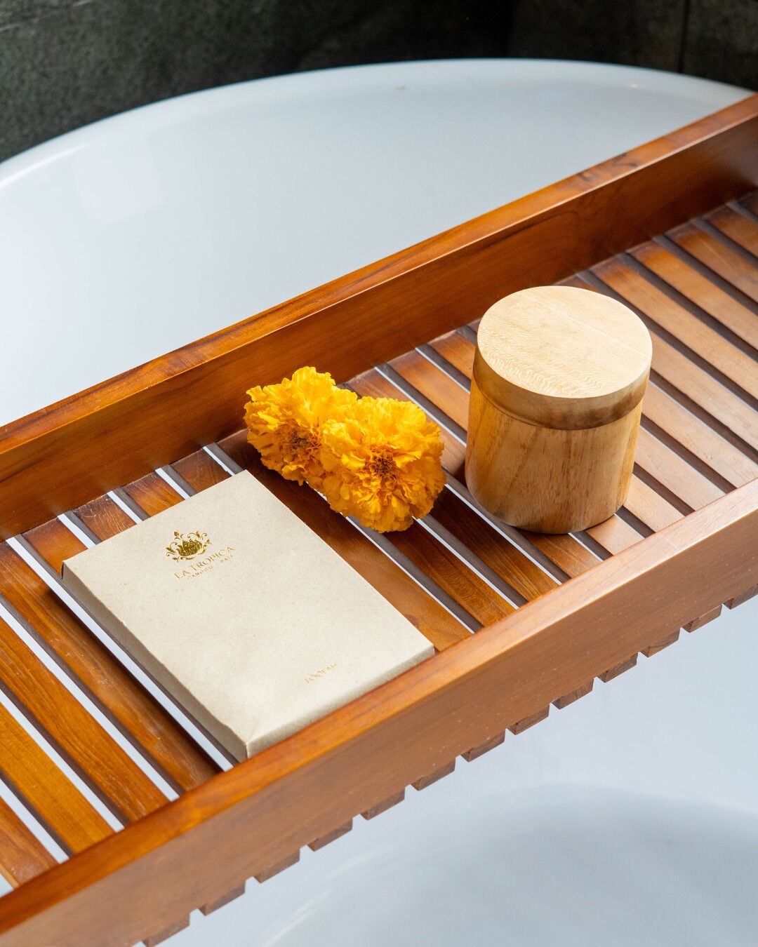 A wooden tray with a white box and a wooden container on a white surface.