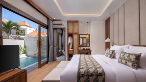 A modern hotel room with a large bed, a TV, a balcony with a pool, and a wooden wardrobe. - La Tropica Canggu Bali (Buduk)