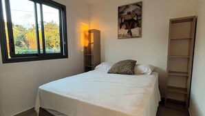 A bedroom with a bed, a window, a wall-mounted shelf, and a ceiling light. - Furnished bungalow sea view (Saint-Pierre)