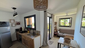 A modern kitchen with a built-in refrigerator, a sink, and a stove. There is a dining area with a table and chairs, and a sofa. - Furnished bungalow sea view (Saint-Pierre)