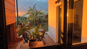A balcony with wooden flooring, a potted plant, and a view of the sky and distant buildings. - Furnished bungalow sea view (Saint-Pierre)