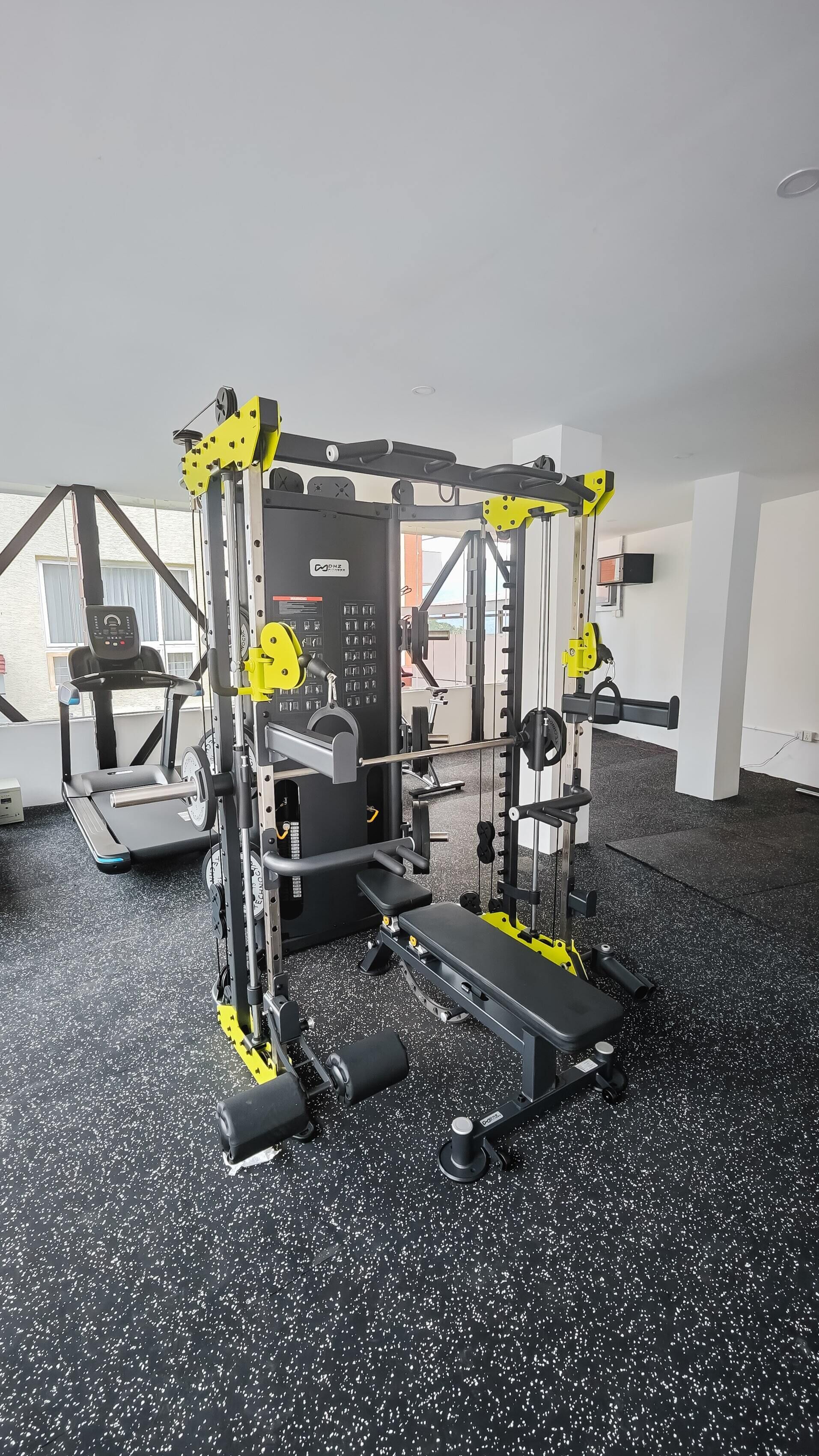 A gym with a variety of exercise equipment, including a treadmill, weight machines, and a bench.