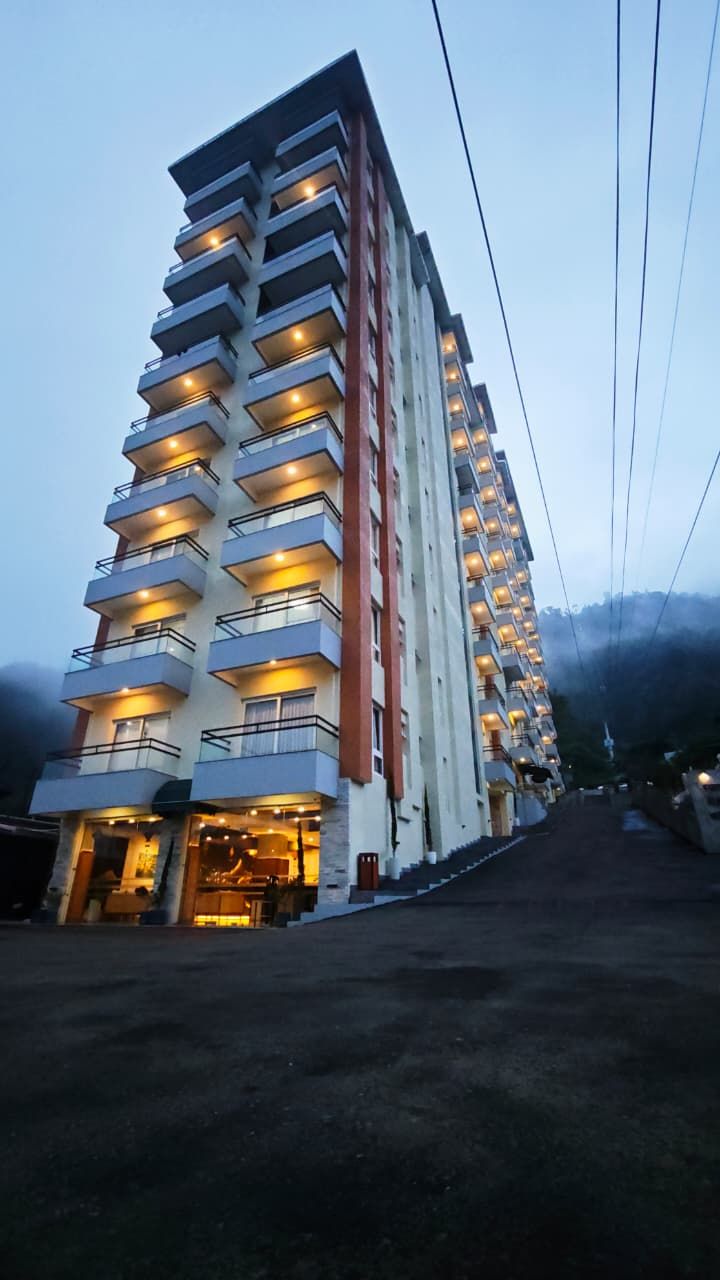Un hotel de varios pisos con balcones, una escalera que conduce a la entrada y vistas del entorno.