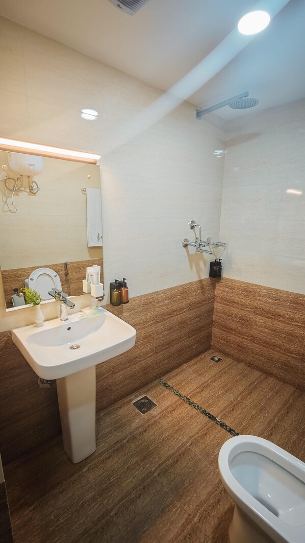 Un baño moderno con un lavamanos blanco, inodoro y zona de ducha.