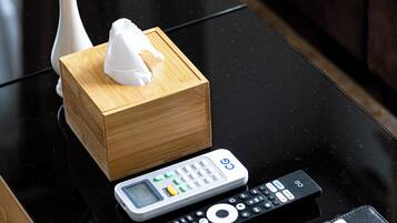 A black glass coffee table with a remote control, a tissue box, and a plant.