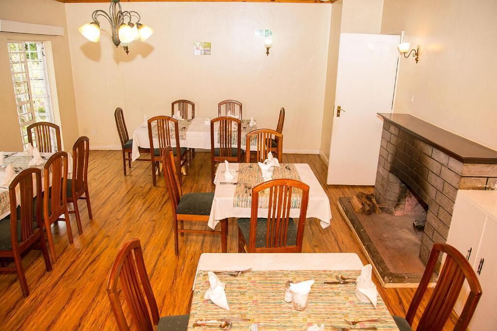 A dining area with wooden chairs and tables, a fireplace, and a chandelier.