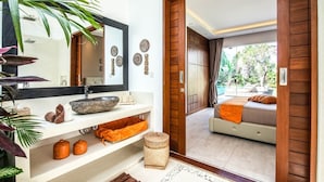 A modern bathroom with a large mirror, stone basin, and shelves with towels and toiletries. - Stunning 6 Bedroom Villa Only 400m to the Beach (Canggu)