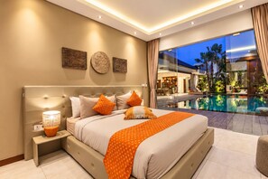 A modern hotel room with a large bed, a nightstand, a lamp, and a view of an outdoor swimming pool.