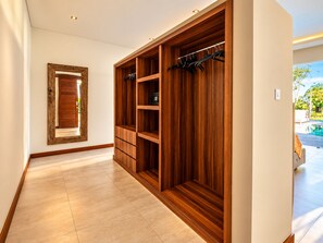 A hallway with a wooden wardrobe, a mirror, and a view of an outdoor swimming pool.