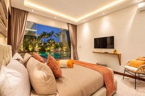 A modern bedroom with a large bed, a TV, a pool view, and a chair.