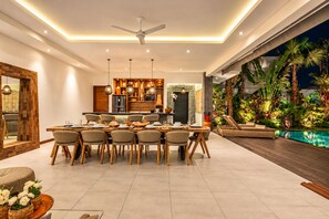 A modern dining area with a central table, chairs, and a ceiling fan.