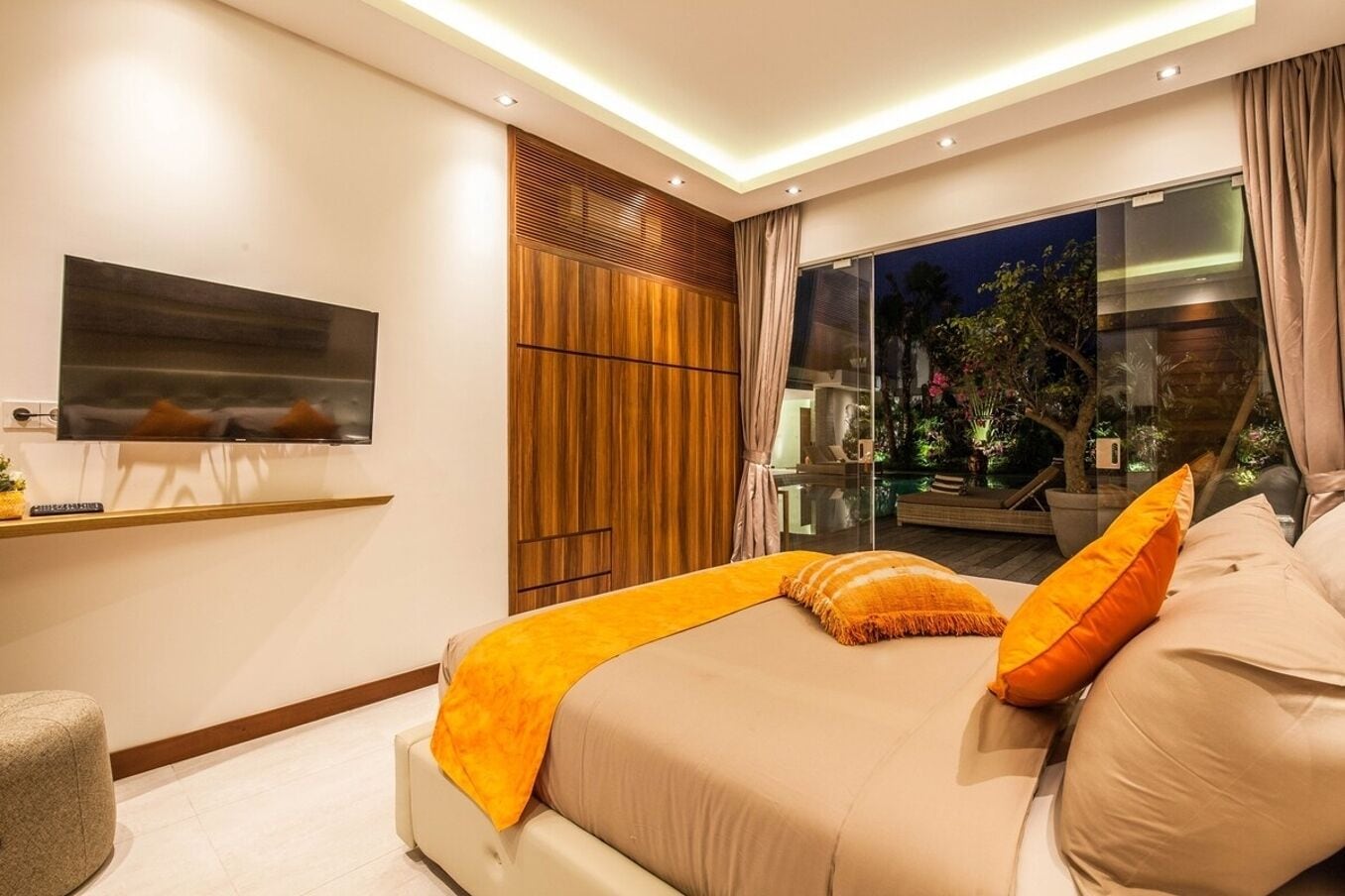 Een moderne slaapkamer met een groot bed, een tv aan de muur en uitzicht op het buiten.