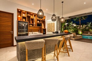 A modern kitchen with a central island, bar stools, and pendant lighting.
