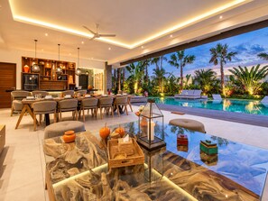 A modern interior with a dining area, kitchen, and a poolside view.