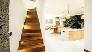 A modern kitchen with a central island, wooden staircase, and pendant lighting. - Seaside Luxury: 4BR Villa, 400m to Finns, Canggu (Canggu)