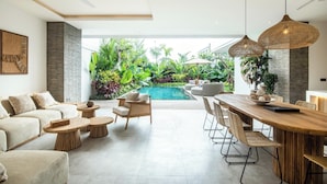A modern living room with a pool, outdoor seating, and a dining area. - Seaside Luxury: 4BR Villa, 400m to Finns, Canggu (Canggu)