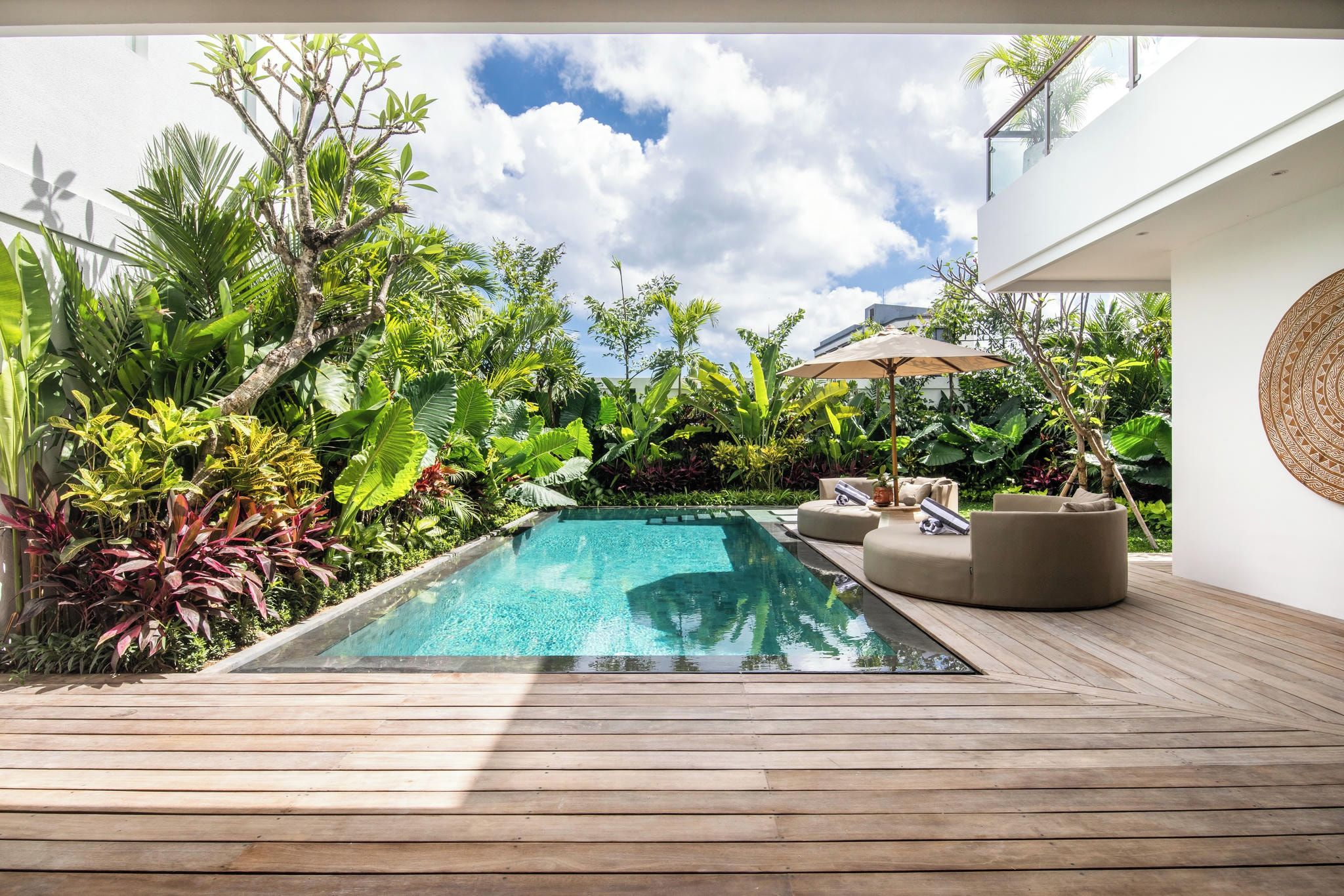 A poolside area with a wooden deck, a lounge chair, and a small table.