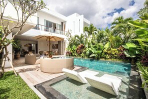 Une maison moderne dotée d’une piscine, d’un espace salon extérieur et d’une végétation tropicale luxuriante.